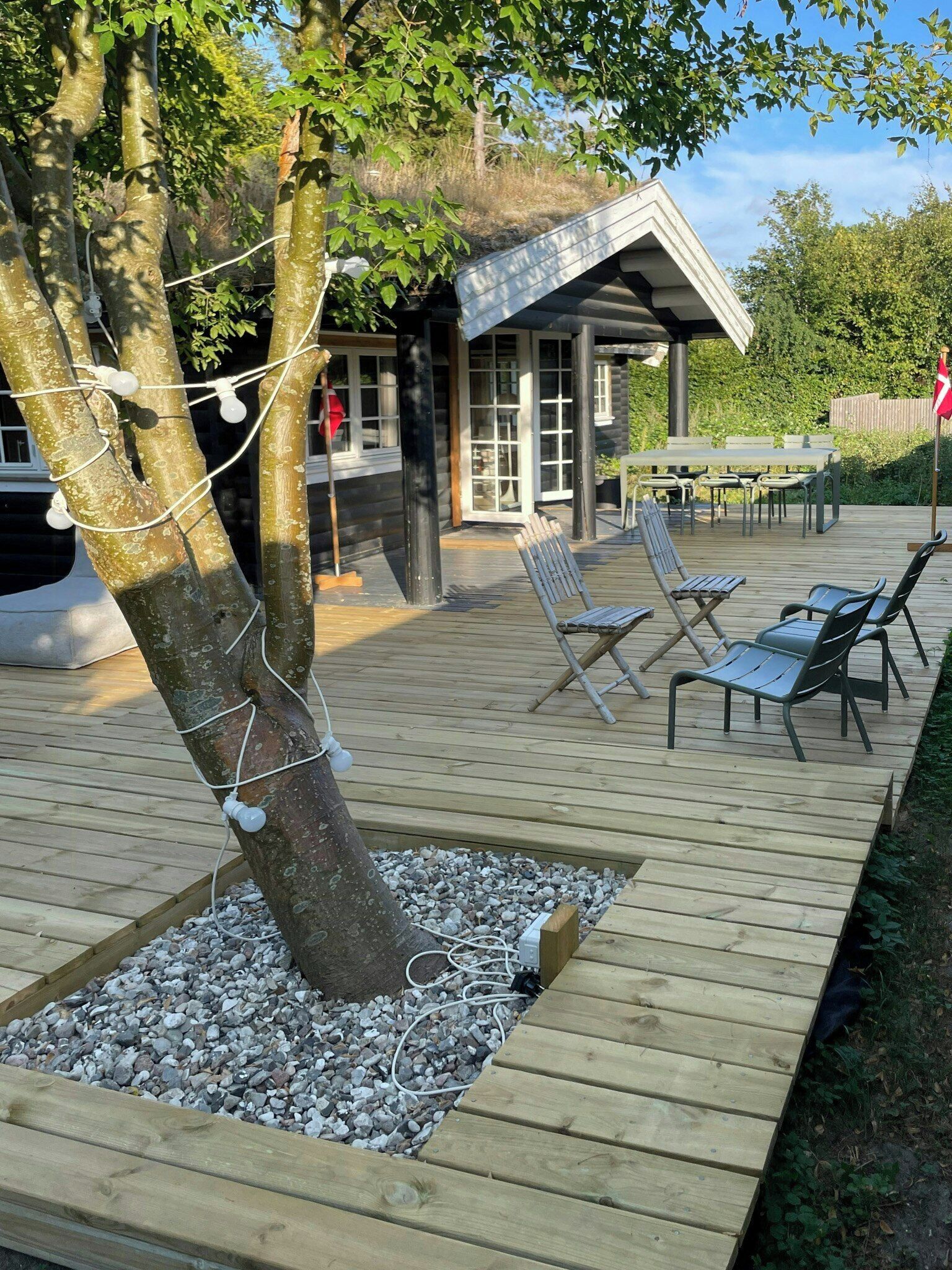 A wooden deck with outdoor seating and a building in the background.
