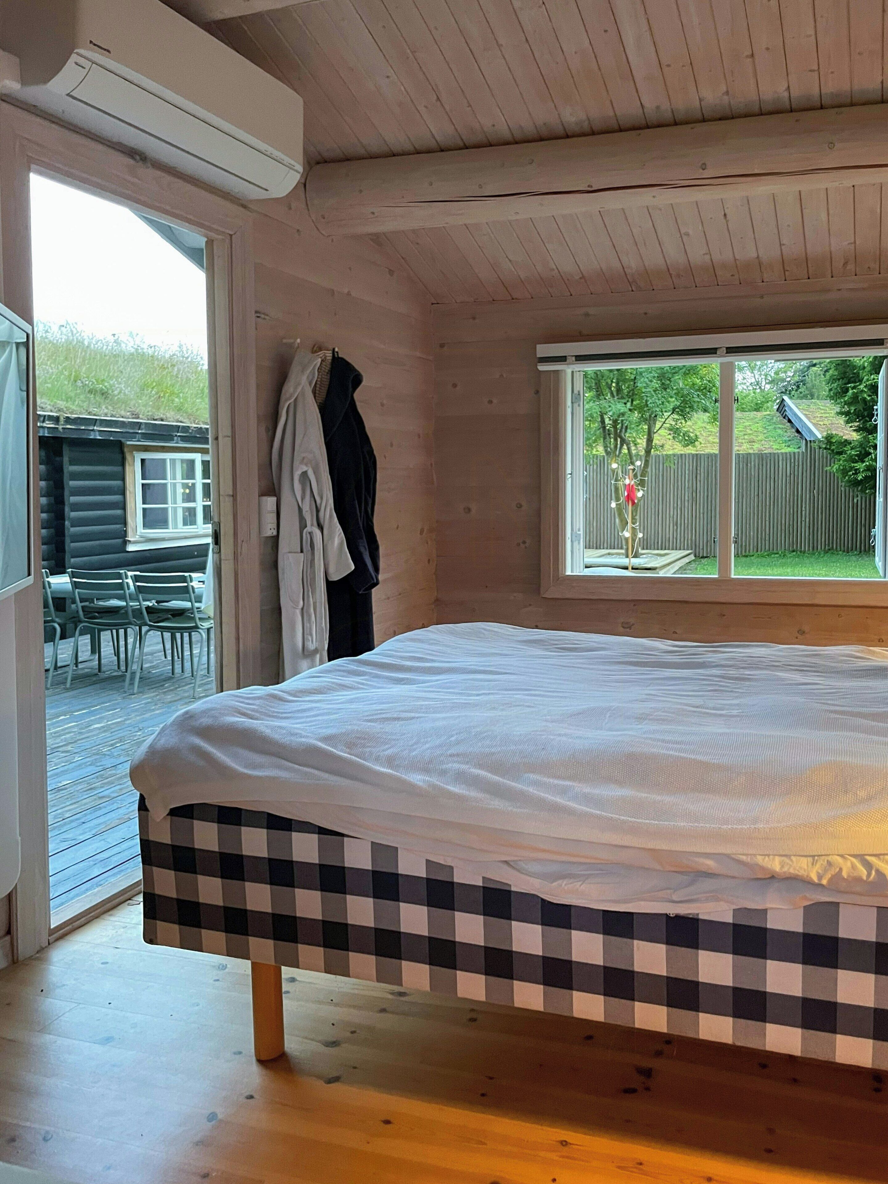 A bedroom with a bed, a window, and a view of the outdoors.