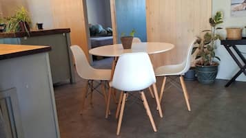 Un comedor moderno con una mesa redonda y sillas blancas, una encimera de madera y una puerta corredera tipo granero.
