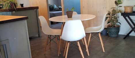 A modern dining area with a round table and white chairs, a wooden counter, and a sliding barn door.