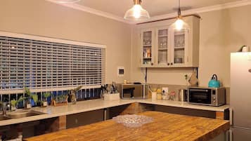 A kitchen with a central island, overhead pendant lights, a microwave, a toaster, and a refrigerator.