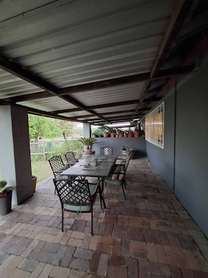 An outdoor covered patio with a long table and chairs, surrounded by potted plants. - Rustic Farmhouse Retreat in Cape Winelands, South Africa (Paarl)