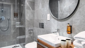 A modern bathroom with a glass-enclosed shower, a toilet, and a vanity with a mirror and sink. - My Second Home - Nekázanka 17 Residence (Hlavní město Praha)