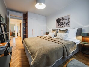 Ein modernes Schlafzimmer mit einem großen Bett, einem Nachttisch, einer Lampe und einem Kleiderschrank.