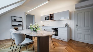 A modern kitchen with a central island, built-in appliances, and a herringbone wood floor. - My Second Home - Nekázanka 17 Residence (Hlavní město Praha)