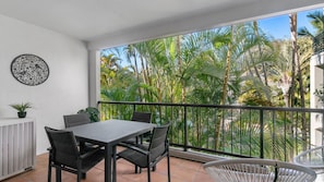 Ein Balkon mit Tisch und Stühlen, einem Blumentopf und einer Wanddekoration.