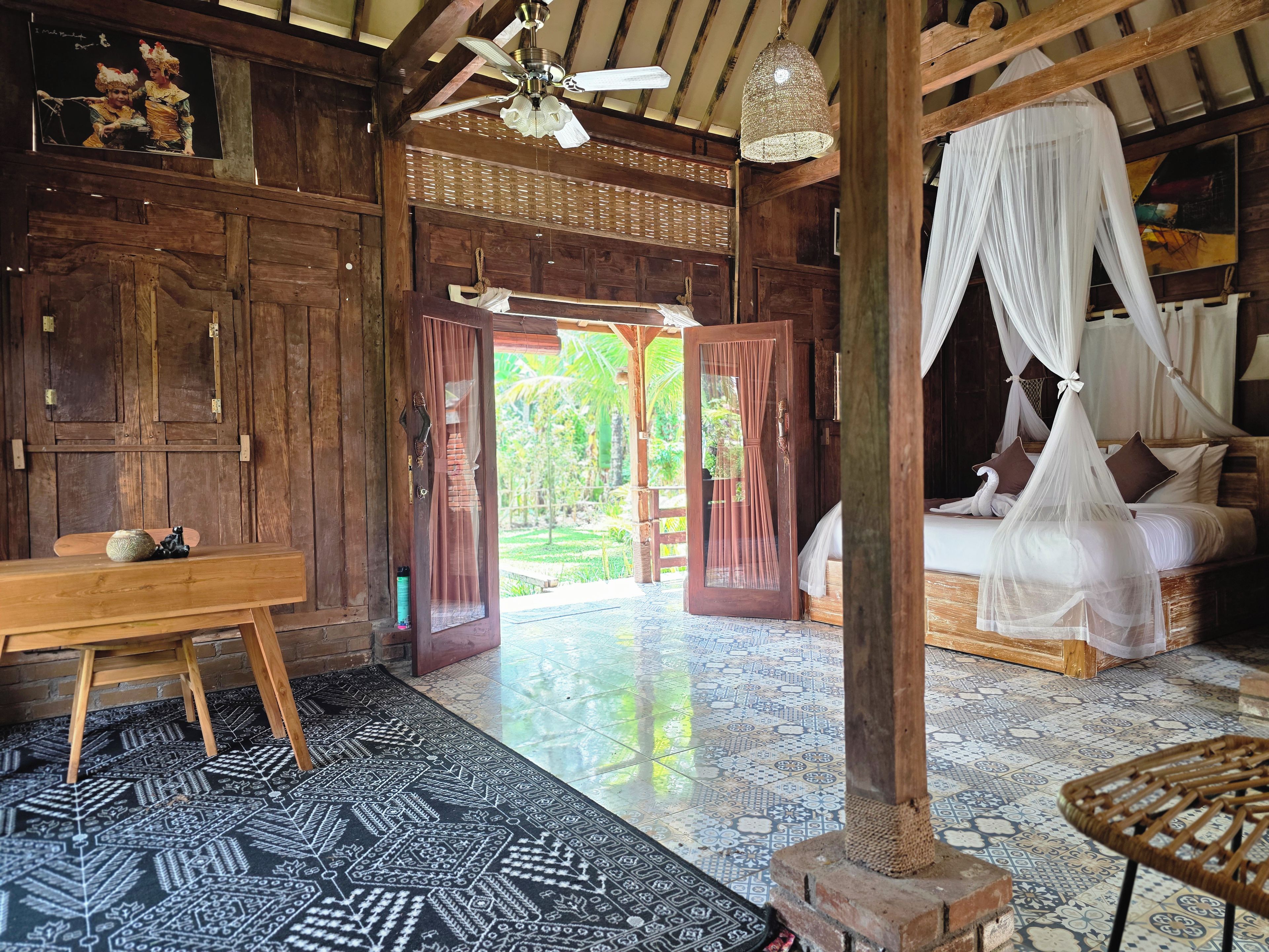 Een klassieke houten kamer met een bed, een bankje en uitzicht op het landschap.