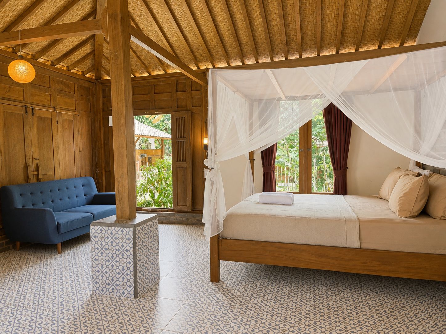 A room with a bed under a canopy, a blue sofa, and a patterned floor.