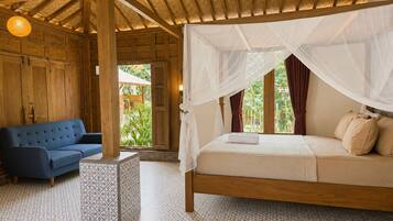 A room with a bed under a canopy, a blue sofa, and a patterned floor.