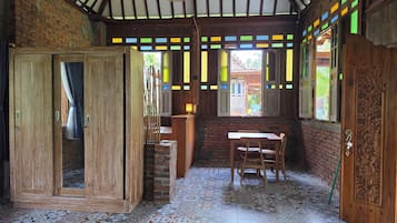 Una habitación con suelo de baldosas, muebles de madera, una puerta de madera con intrincados grabados y un ventanal con vidrieras de colores.