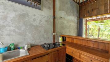 A compact kitchen with a sink, a stove, and a window overlooking a garden.
