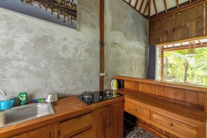 Una cucina compatta con lavandino, fornelli e finestra vista giardino.
