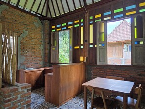 A rustic interior with exposed brick walls, wooden furniture, and a tiled floor. - Sangeh Lodge (Abiansemal)