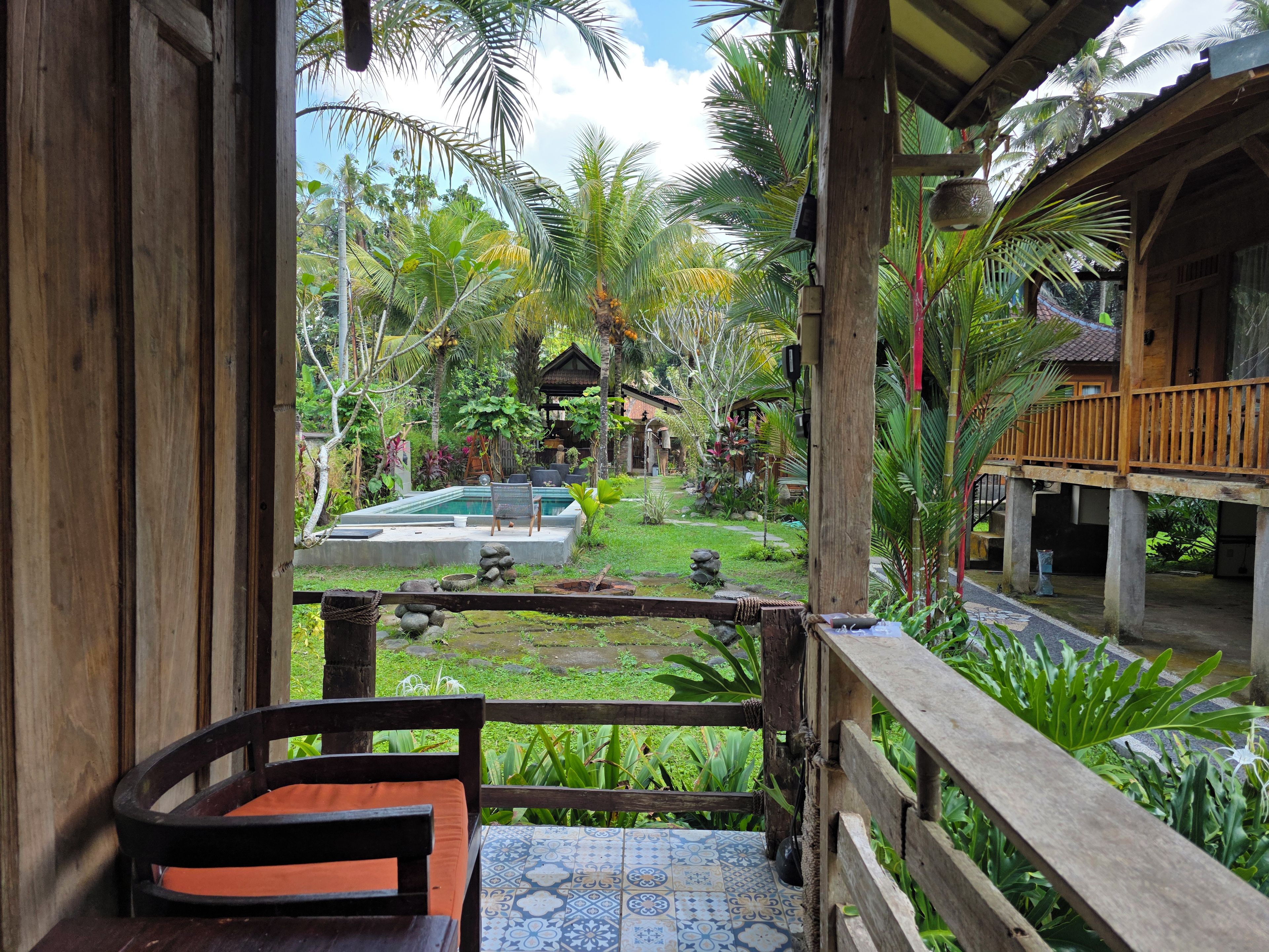Un balcón de madera con vista a una piscina y jardín tropical.