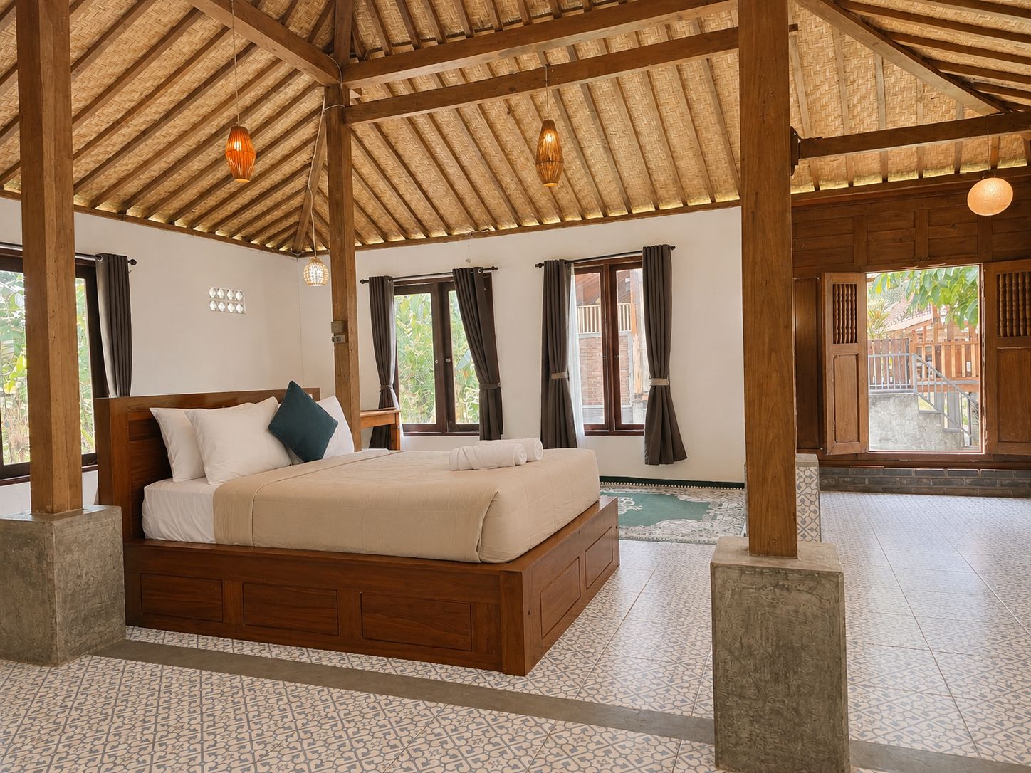 A spacious bedroom with a large bed, wooden beams, and a view of the outside.
