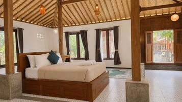 A spacious bedroom with a large bed, wooden beams, and a view of the outside.