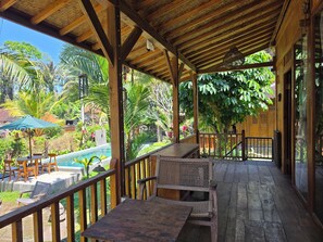 Un'area esterna coperta con piscina, arredi in legno e vegetazione rigogliosa.