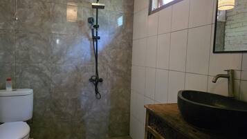 A bathroom with a shower, toilet, sink, and a window.