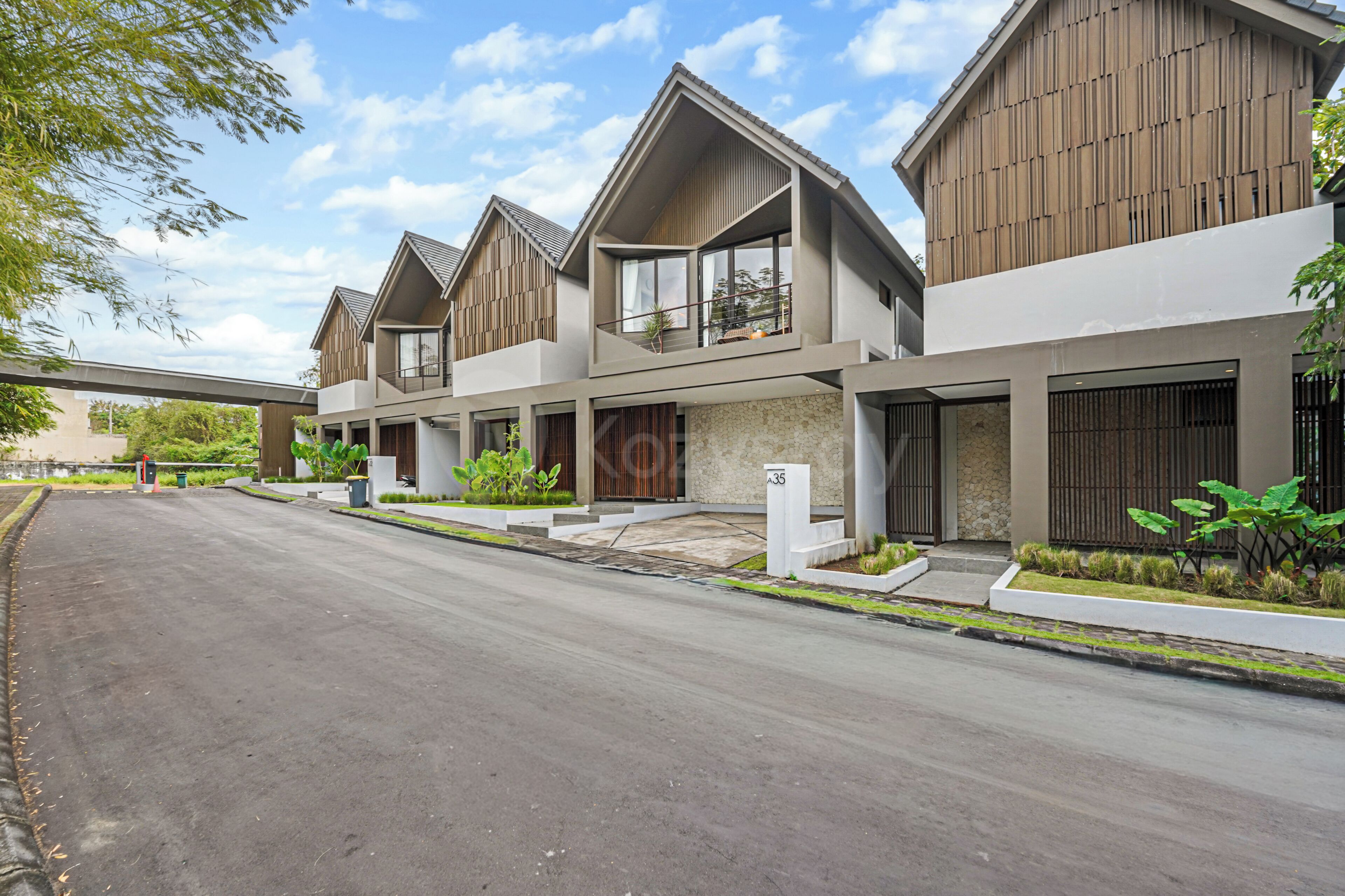 A modern residential building with a two-story structure, a covered driveway, and a landscaped front yard.