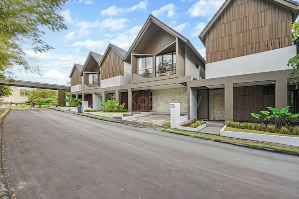 A modern residential building with a two-story structure, a covered driveway, and a landscaped front yard.