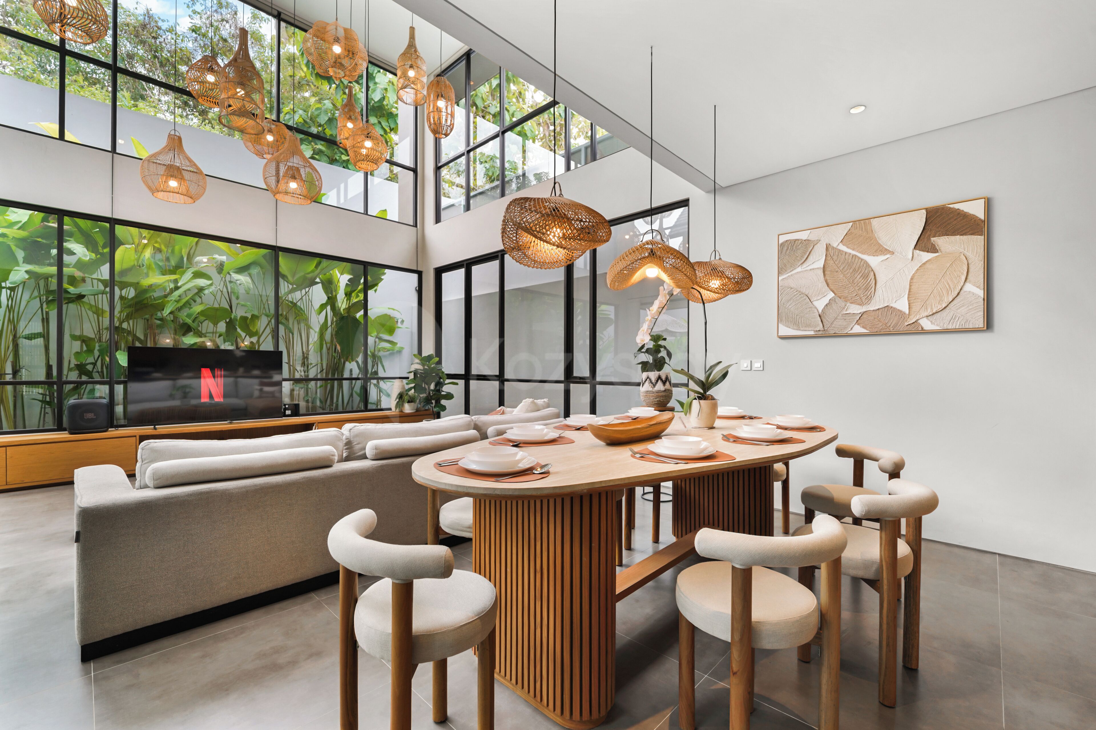 A modern living room with a large window, a dining area with a round table, and a sofa.