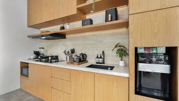 A modern kitchen with wooden cabinets, a built-in stove, and a black refrigerator.