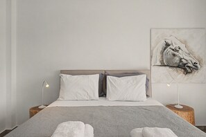 A bedroom with a bed, two bedside lamps, a headboard, and a painting on the wall. - Kalliopi's Apartment with Stunning Acropolis View (Athens)