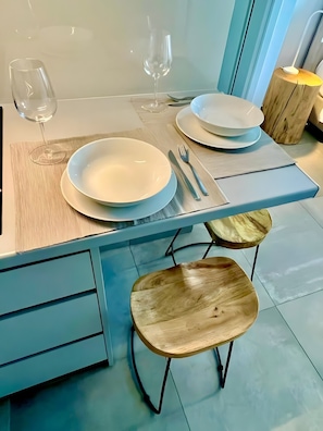Uma área de refeições com uma mesa posta para dois, apresentando um prato branco, um garfo e uma faca.