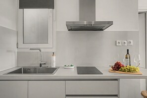 A modern kitchen with a stainless steel sink, a built-in oven, and a range hood. - Kalliopi's Apartment with Stunning Acropolis View (Athens)