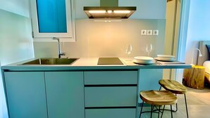 A modern kitchen with a built-in island, stainless steel sink, and bar stools. - Kalliopi's Apartment with Stunning Acropolis View (Athens)