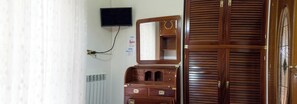 A room with a wooden wardrobe, a mirror, a television mounted on the wall, and a radiator. - IN THE HISTORIC CENTER: A WONDERFUL APARTMENT EQUIPPED WITH ALL THE AMENITIES AND SERVICES (Napoli)