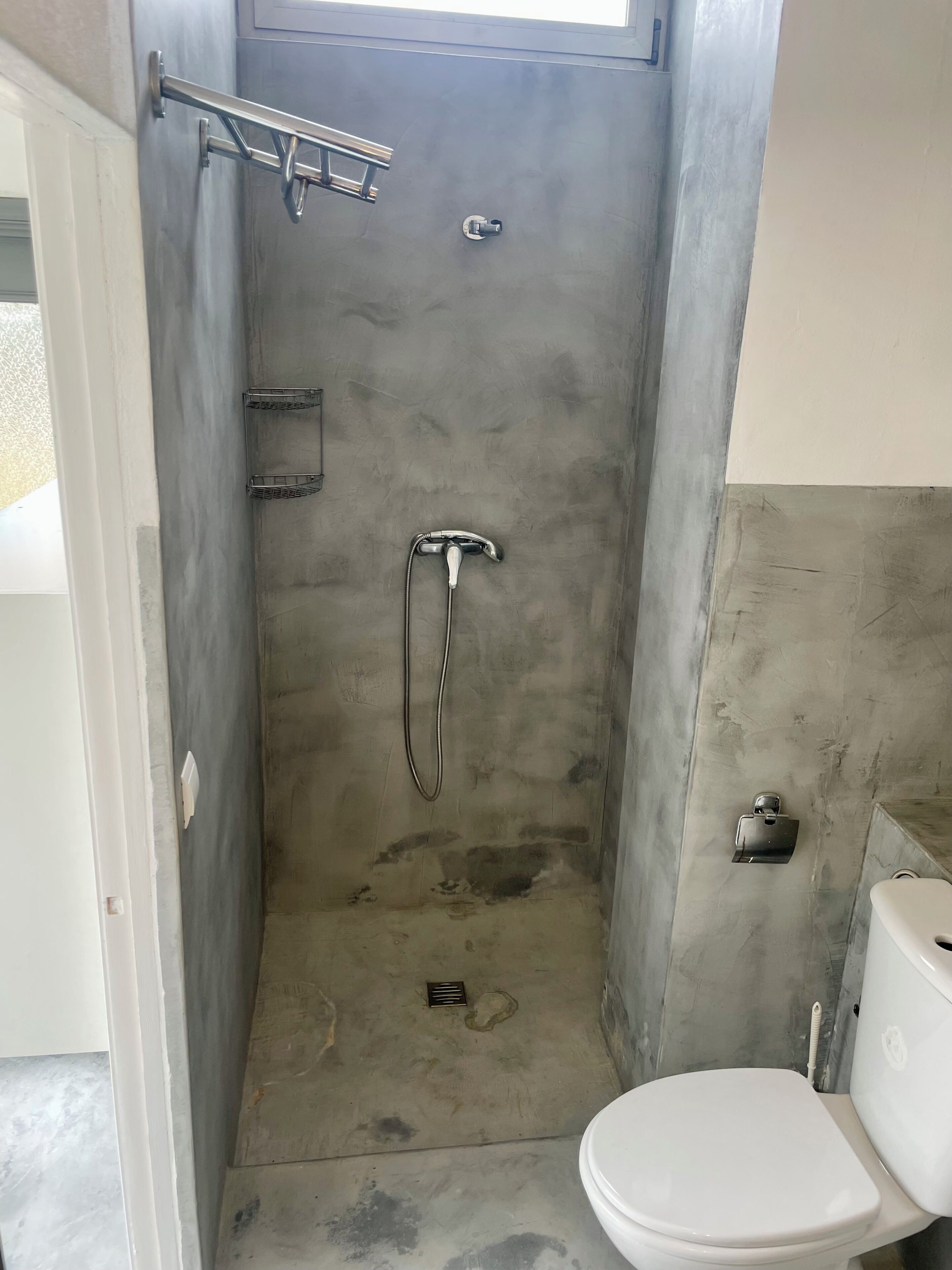 Un baño pequeño con ducha, inodoro y un perchero para toallas.