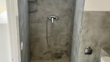 Un baño pequeño con ducha, inodoro y un perchero para toallas.