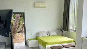 Ein modernes Schlafzimmer mit Bett, Fernseher, Deckenventilator und einem Fenster mit Vorhängen.