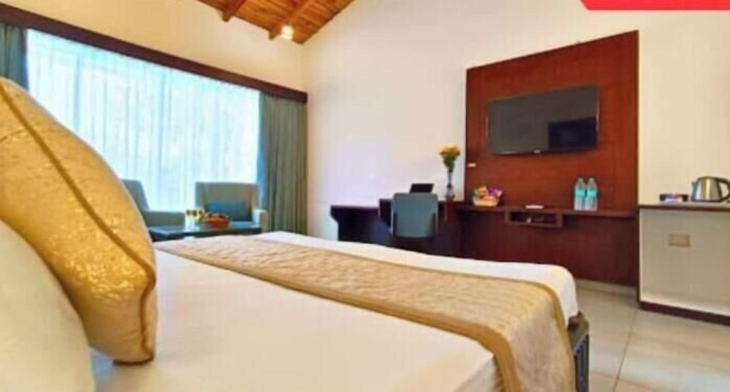 A hotel room with a bed, a desk, a television, and a window with curtains.