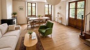 A spacious living room with a wooden dining table, a green armchair, a sofa, and a fireplace. - Country house in the heart of the Ardèche, near Valence, with mountain views (Saint-Laurent-du-Pape)