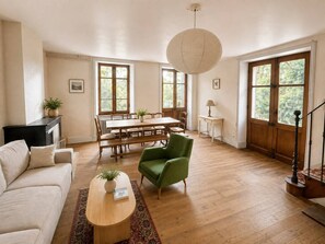 A spacious living room with a wooden dining table, a green armchair, a sofa, and a fireplace. - Country house in the heart of the Ardèche, near Valence, with mountain views (Saint-Laurent-du-Pape)