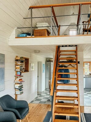 Een kamer in loftstijl met een houten trap, een boekenplank en een geruite vloer.