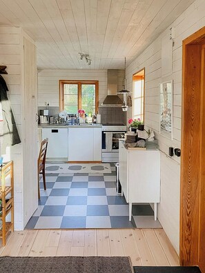 Een keuken met een geruit vloertje, houten kastjes en een raam.