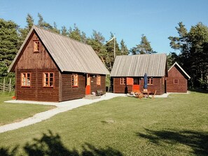 Een rustiek houten gebouw met een metalen dak, een vlaggenmast en een klein terras.