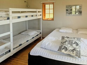 Een slaapkamer met stapelbed, raam en schilderij aan de muur.