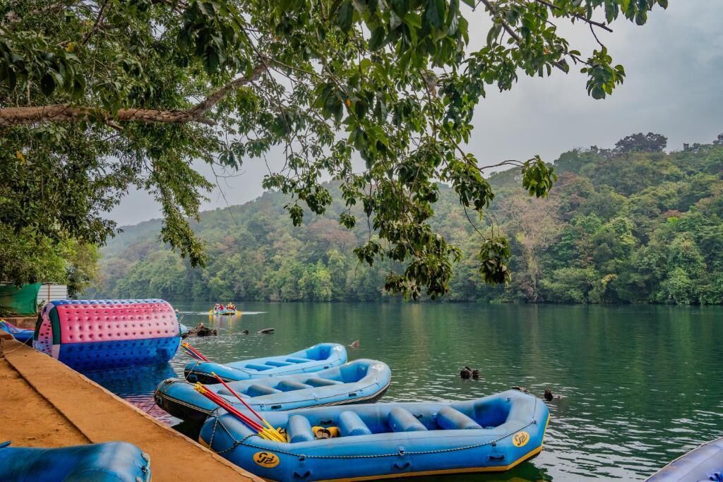 A calm lake with inflatable rafts docked on the shore, surrounded by lush greenery.