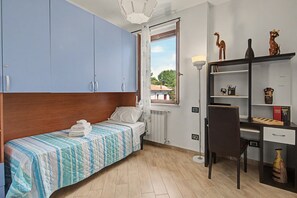Un dormitorio con cama, escritorio y silla. Hay una ventana con vistas al exterior.