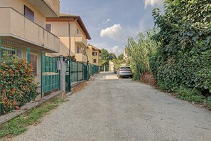 A residential street with houses on both sides, a gravel road, and a parked car.