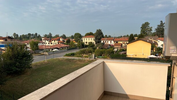 A balcony with a view of a residential area, a paved floor, and a wall.