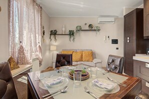 Un comedor con una mesa dispuesta para cuatro, un sofá con cojines y una estantería colgante para plantas.