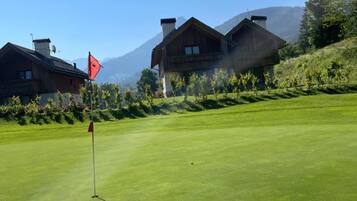 Ein Golfplatz mit Fahnenstange, einer roten Fahne und einem Gebäude im Hintergrund.
