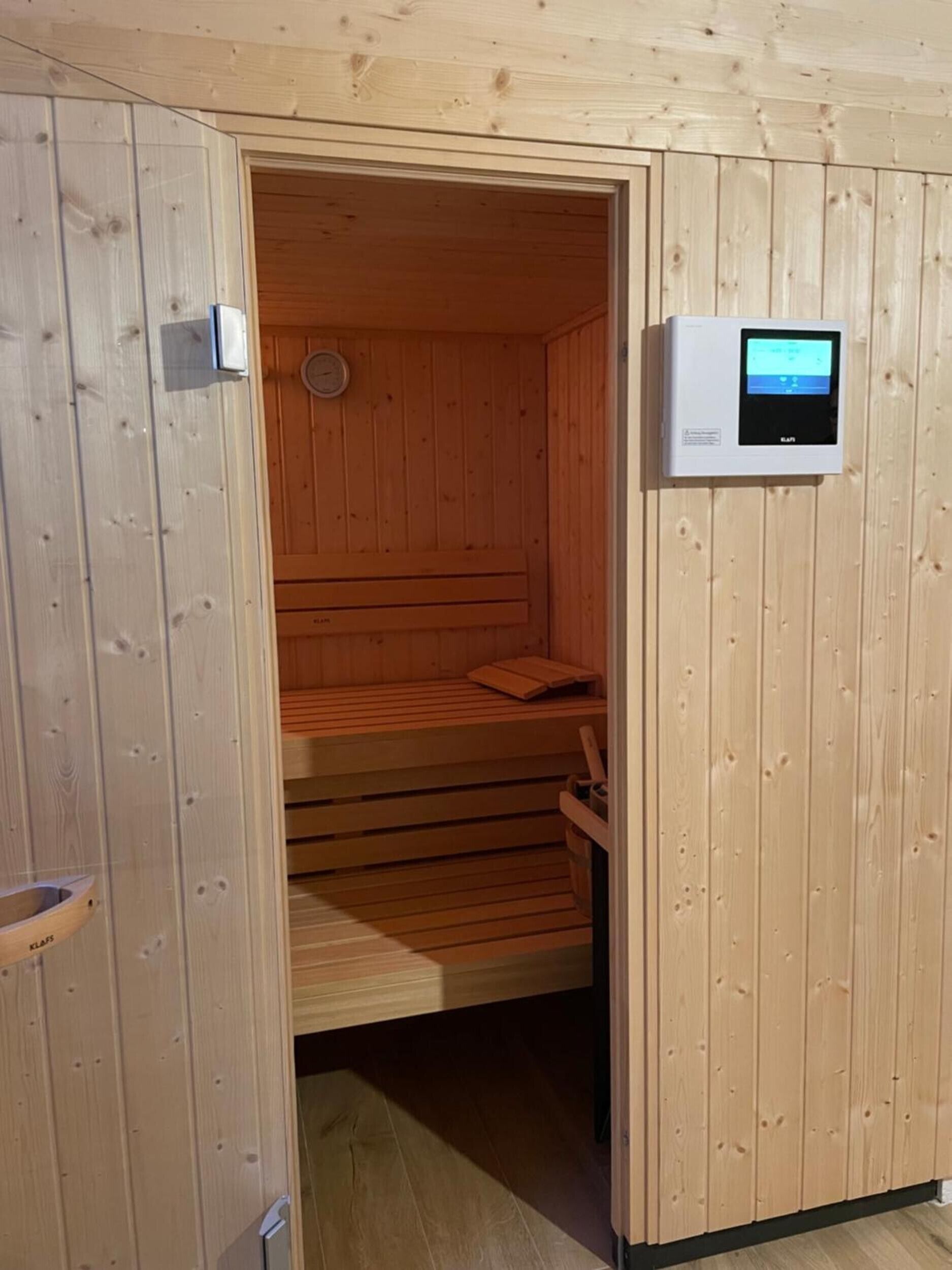 Saunahuone, jonka seinät ovat puuta ja jossa on ohjauspaneeli.