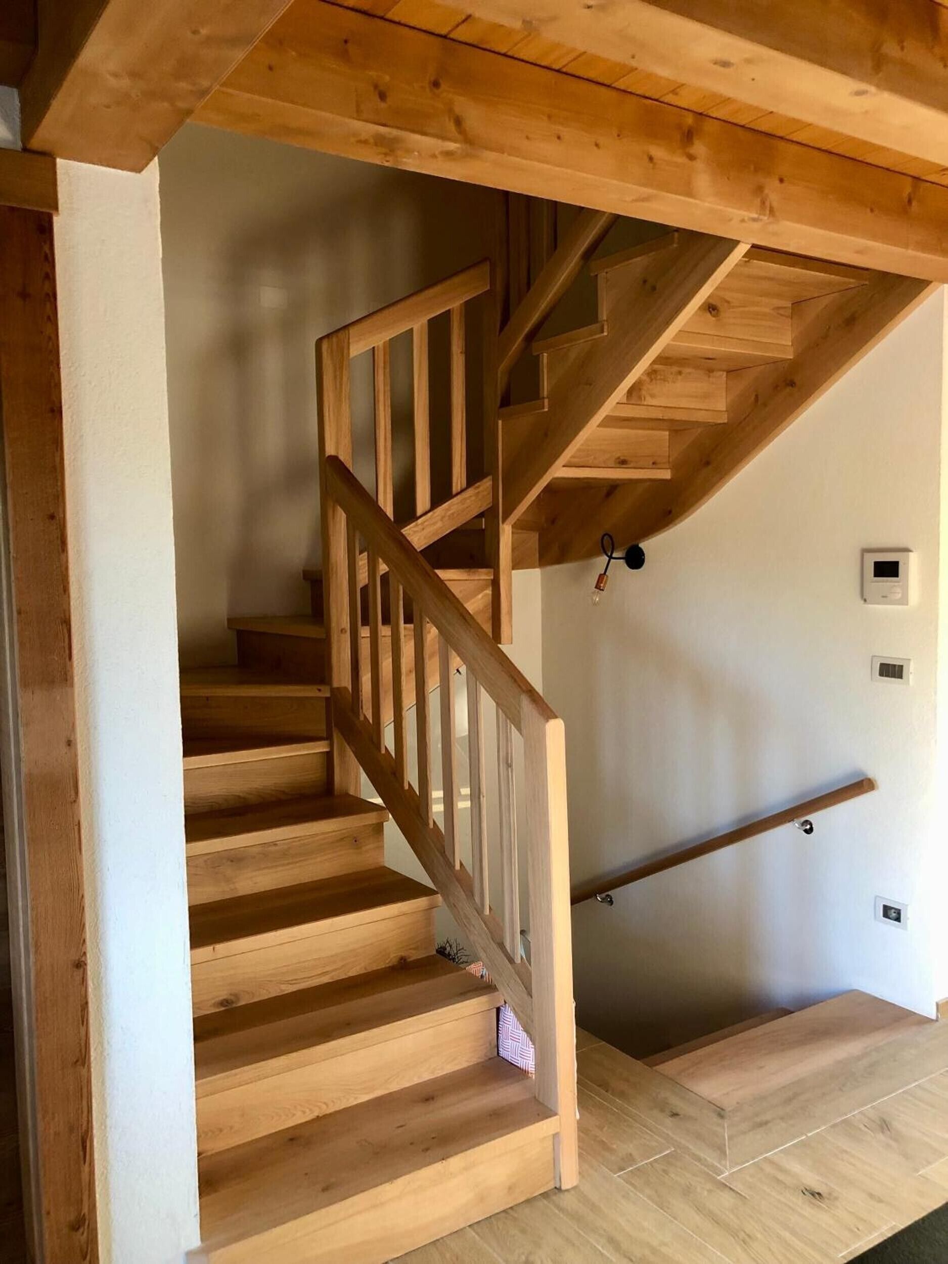 A wooden staircase with a handrail leading to a landing.