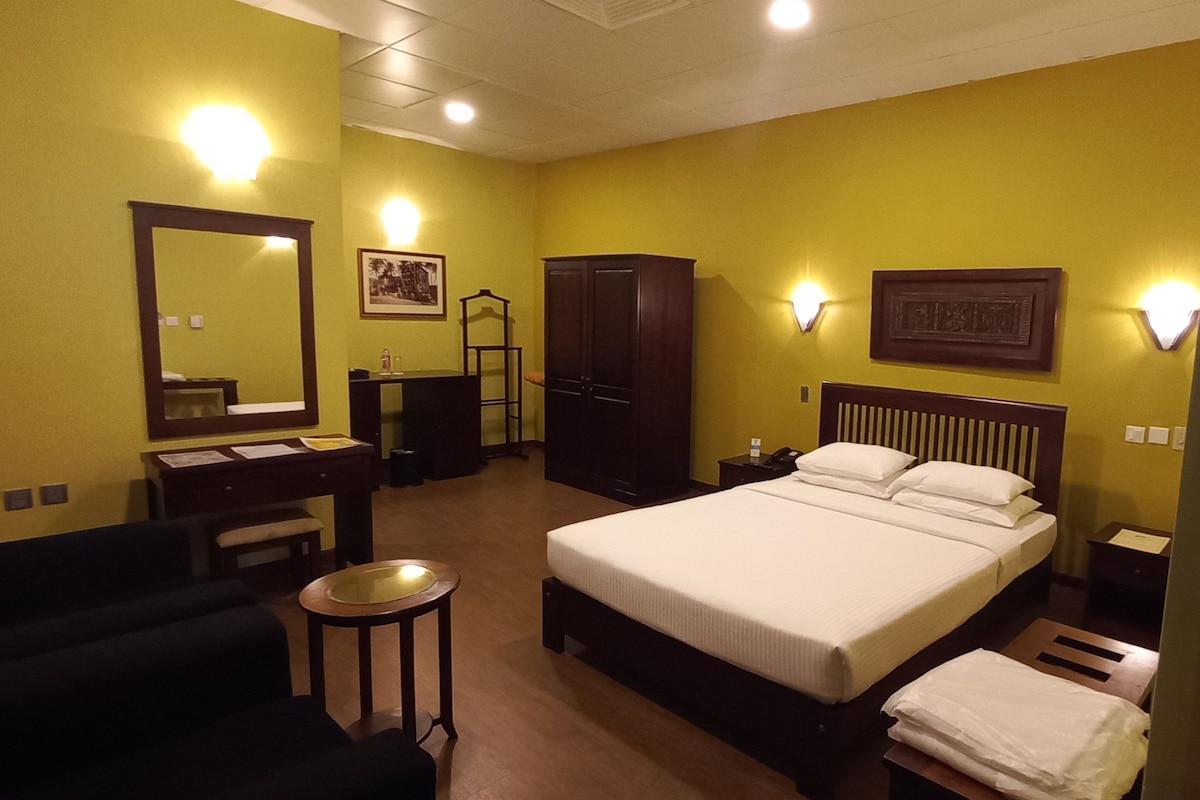 Ein Hotelzimmer mit Bett, Nachttisch, Kleiderschrank und Spiegel.